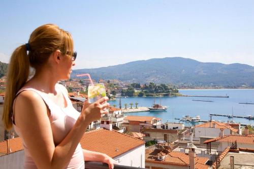 a woman standing on a balcony with a drink at Kaplanis House in Neos Marmaras