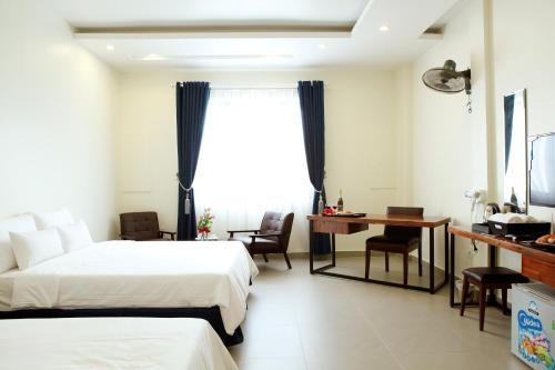 a hotel room with two beds and a desk at Noblesse Hotel in Hai Phong