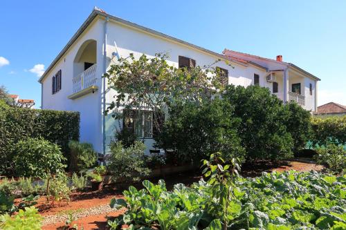 a white house with a garden in front of it at Apartment Zora in Zadar