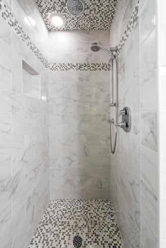 a bathroom with a shower with white tiles at The Quarters on Vendue in Charleston