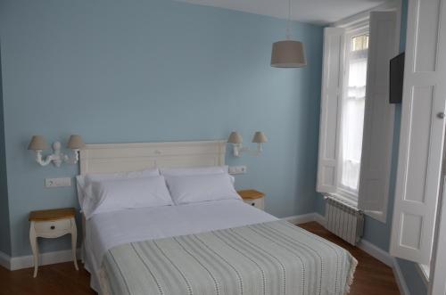 a bedroom with a bed with white sheets and a window at A Casa dos Nores Charming House in Cangas de Morrazo