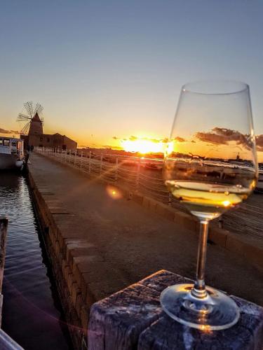 a glass of wine sitting on a table with the sunset at Sirio Marsala in Birgi Vecchi