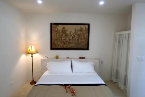 a bedroom with a white bed with a painting on the wall at Hotel Casa de Campo Conkal Merida in Conkal