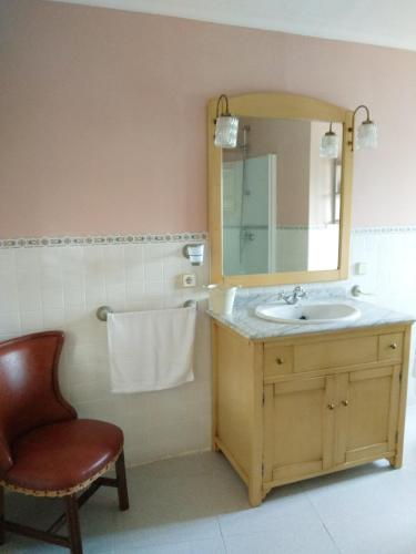 a bathroom with a sink and a mirror and a chair at La Torre Mondariz in Mondariz