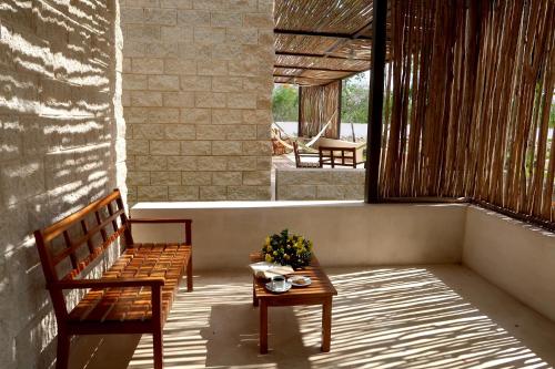 a porch with two benches and a table with flowers at Hotel Casa de Campo Conkal Merida in Conkal