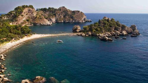 an island in the ocean with a boat in the water at A casa di Edo in Acireale