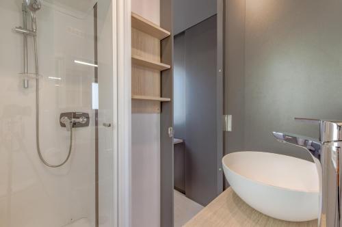 La salle de bains est pourvue d'un lavabo blanc et d'une douche. dans l'établissement Camping le Mas de Riri, à Celles
