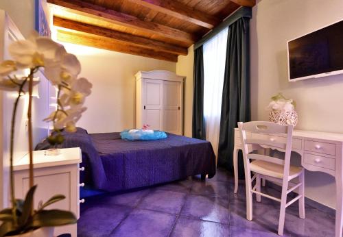 a bedroom with a purple bed and a table and chair at Residenza Vinci Room & Suite in Pizzo