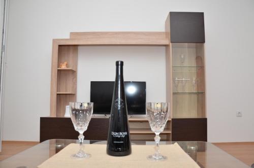 een fles wijn en twee glazen op een tafel bij Apartman Ksenija in Banja Koviljača