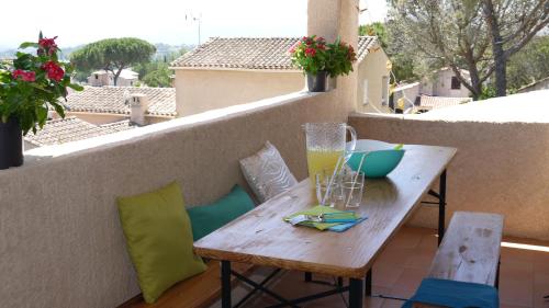 - une table en bois sur un balcon avec une boisson dans l'établissement Grand Appartement dans Maison avec Piscine Privée, à Fréjus