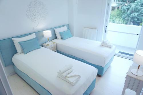 two beds in a room with a window at Colours Seaview Apartment in Nea Artaki