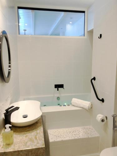 a white bathroom with a sink and a bath tub at Colours Seaview Apartment in Nea Artaki