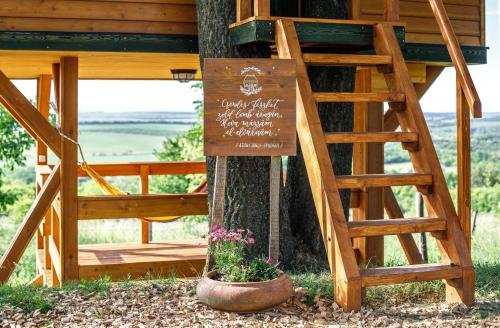 a sign on a tree in front of a tree house at Dióliget - Zöld Fészek Lombház in Lovasberény