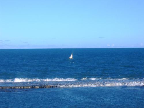a boat in the ocean with a sail boat at Suites Enseada Beira Mar in Coruripe