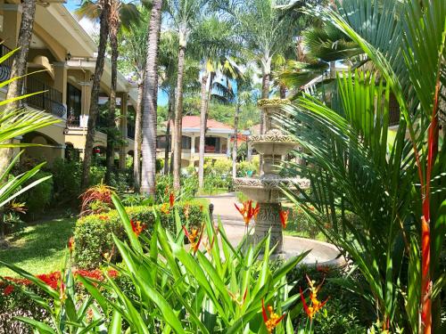a garden with a fountain in front of a house at Monte Carlo Luxury Condominiums in Jacó