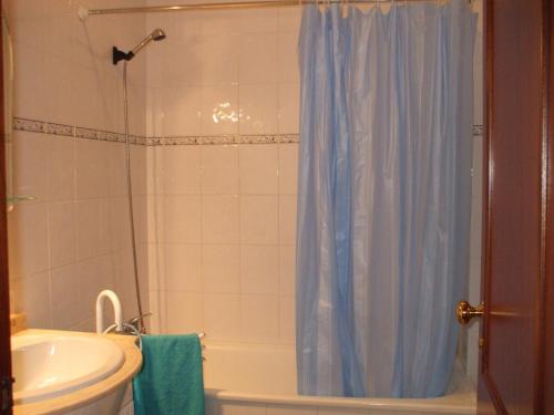 a bathroom with a shower with a blue shower curtain at Casa de Praia da Lú in Figueira da Foz