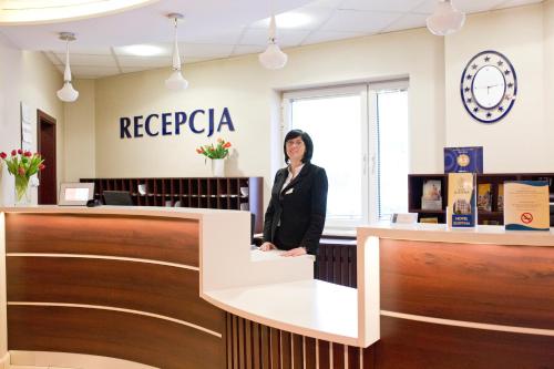 a woman standing in front of a counter with a clock on it at Hotel Justyna in Krakow