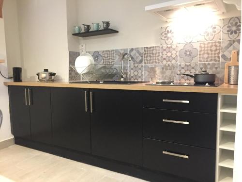 une cuisine avec des armoires noires et un comptoir dans l'établissement Le Verdun 128, à Carcassonne