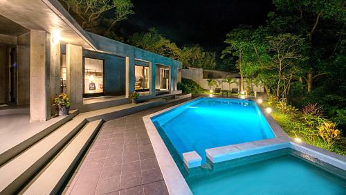 a swimming pool in the backyard of a house at night at Magachabaru Okinawa in Nakijin