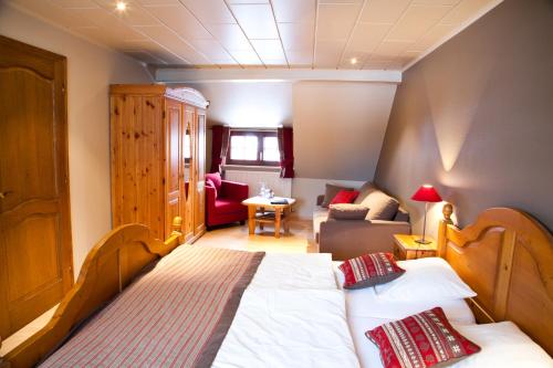 a bedroom with two beds and a living room at Hotel Bütgenbacher Hof in Butgenbach