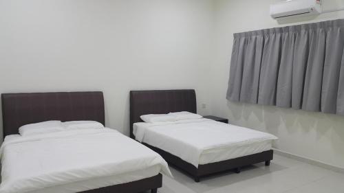 two beds in a room with white sheets at My STW Home 2 in Sitiawan