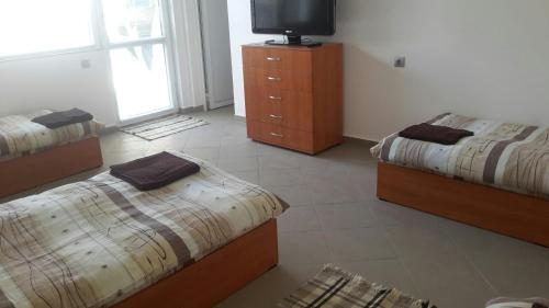 1 dormitorio con 2 camas y un tocador con TV en Guesthouse Tatyana, en Pŭrvenets