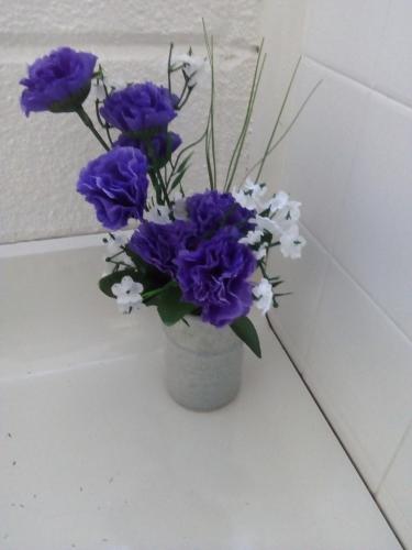 a vase filled with purple and white flowers at Redwood Lodge Motel in Levin