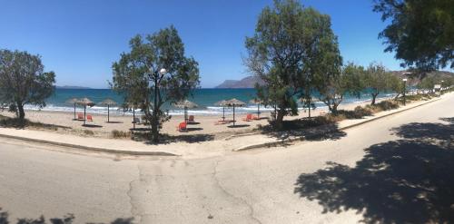 a beach with umbrellas and chairs and the ocean at Rooms Leonidas in Kissamos