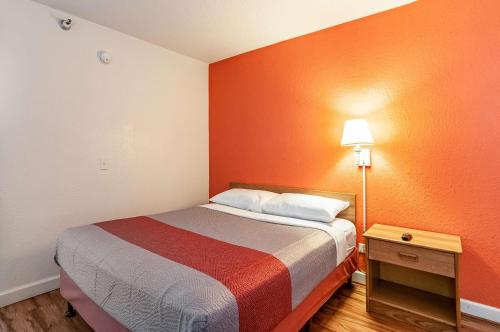 a small room with a bed with an orange wall at Motel 6-Naperville, IL in Naperville