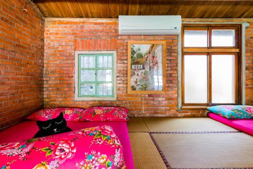 a room with pink beds and a black cat sitting on them at Lungta BnB in Jiufen