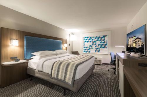 um quarto de hotel com uma cama e uma televisão de ecrã plano em Wingate Augusta Washington Road by Wyndham em Augusta