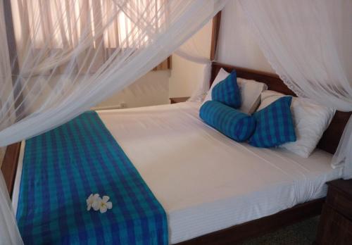 a bedroom with a bed with blue and white pillows at Sunset Fort Galle in Galle