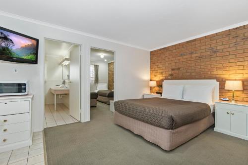 ein Schlafzimmer mit einem Bett und einer Ziegelwand in der Unterkunft Golden Square Motor Inn in Bendigo