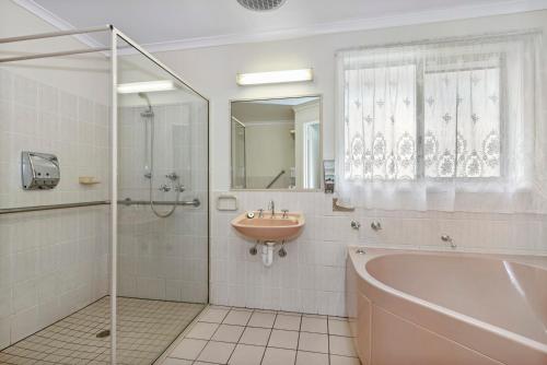 ein Bad mit einer Badewanne, einem Waschbecken und einer Dusche in der Unterkunft Golden Square Motor Inn in Bendigo