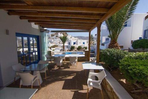 a patio with tables and chairs and a pool at Avanti in Ios Chora