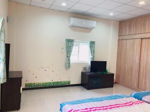 a room with two beds and a tv and a window at Look Tea House in Meishan