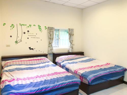 a bedroom with two beds and a window with butterflies on the wall at Look Tea House in Meishan