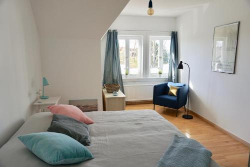 a bedroom with a bed with pillows and a blue chair at Alter Konsumverein App N°9 in Westerland