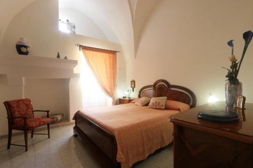ein Schlafzimmer mit einem Bett, einem Stuhl und einem Fenster in der Unterkunft Corte Antica in Presicce