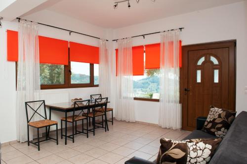 Apartments Villa L&M Skiathos في مدينة سكياثوس: غرفة معيشة مع ستائر برتقالية وطاولة وكراسي