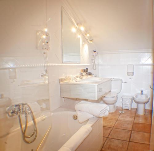 a bathroom with a tub, sink, toilet and bathtub at Hotel Spa El Muelle de Suances in Suances