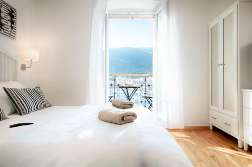 a bedroom with a white bed with a large window at Seafront rooms Koluna in Komiža