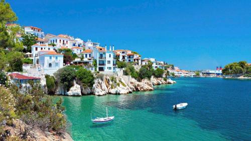 two boats in a body of water with buildings at Apartments Villa L&M Skiathos in Skiathos Town