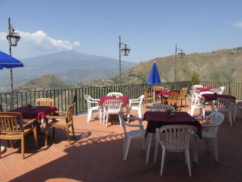 a group of tables and chairs on a deck with mountains at Hotel Panorama di Sicilia in Castelmola
