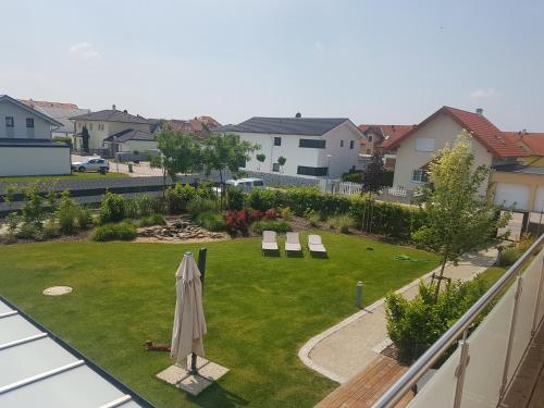 a lawn with an umbrella and chairs and a yard with houses at Pension Laa Natura in Laa an der Thaya