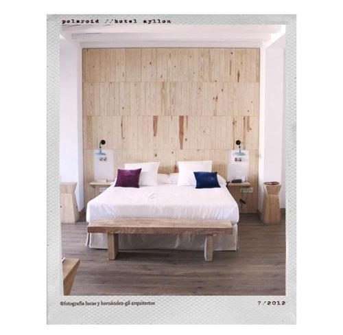 a bedroom with a large white bed with two tables at Hotel Ayllon in Ayllón
