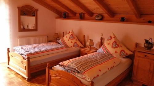 una camera con due letti in una stanza con soffitti in legno di Ferienhaus Hornauer a Obertraubenbach