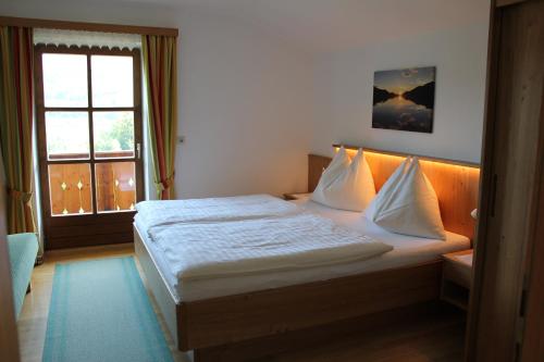 a bed in a room with a large window at Haus Klaushofer in Fuschl am See