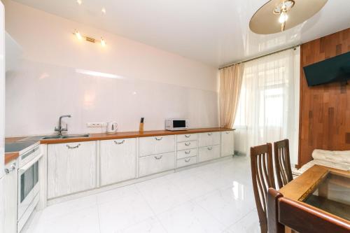 uma cozinha com armários brancos, um lavatório e uma mesa em New building near Arena City Lesi Ukrainky 7a em Kiev