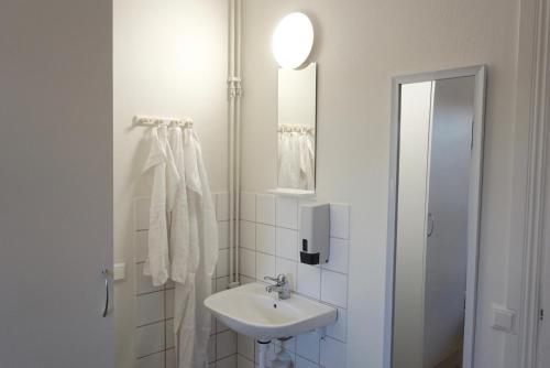 a white bathroom with a sink and a mirror at Gylleby Vandrarhem in Sunne